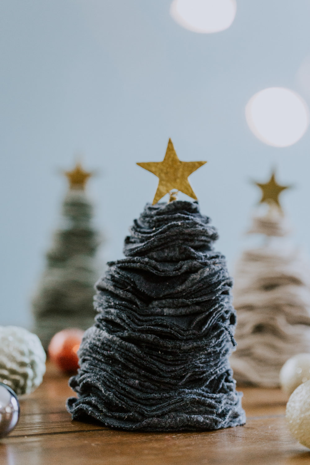 Ethical fair trade upcycled stacked sweater Christmas tree handmade by Grain of Rice Project artisans in Kibera slum, Kenya | This tree is dark denim blue in color and has a brass star topper.