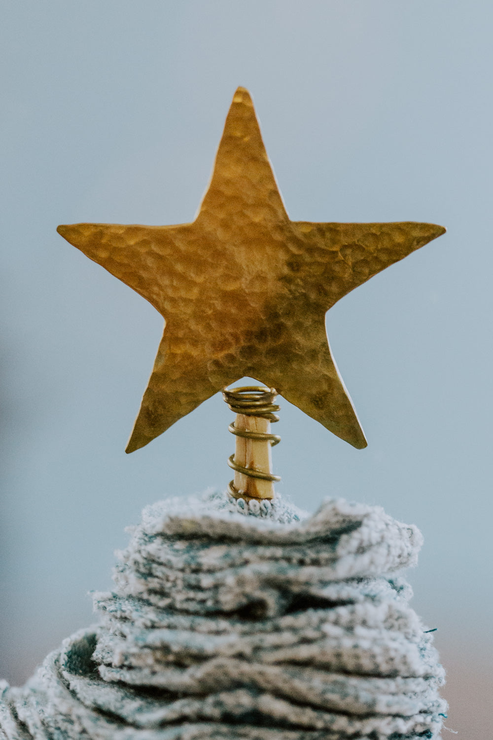 Ethical fair trade upcycled stacked sweater Christmas tree handmade by Grain of Rice Project artisans in Kibera slum, Kenya | This close up of the handmade brass star topper shows its texture.
